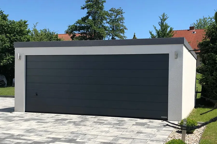 Großraumgarage mit einem breiten anthrazitfarbenen Sektionaltor